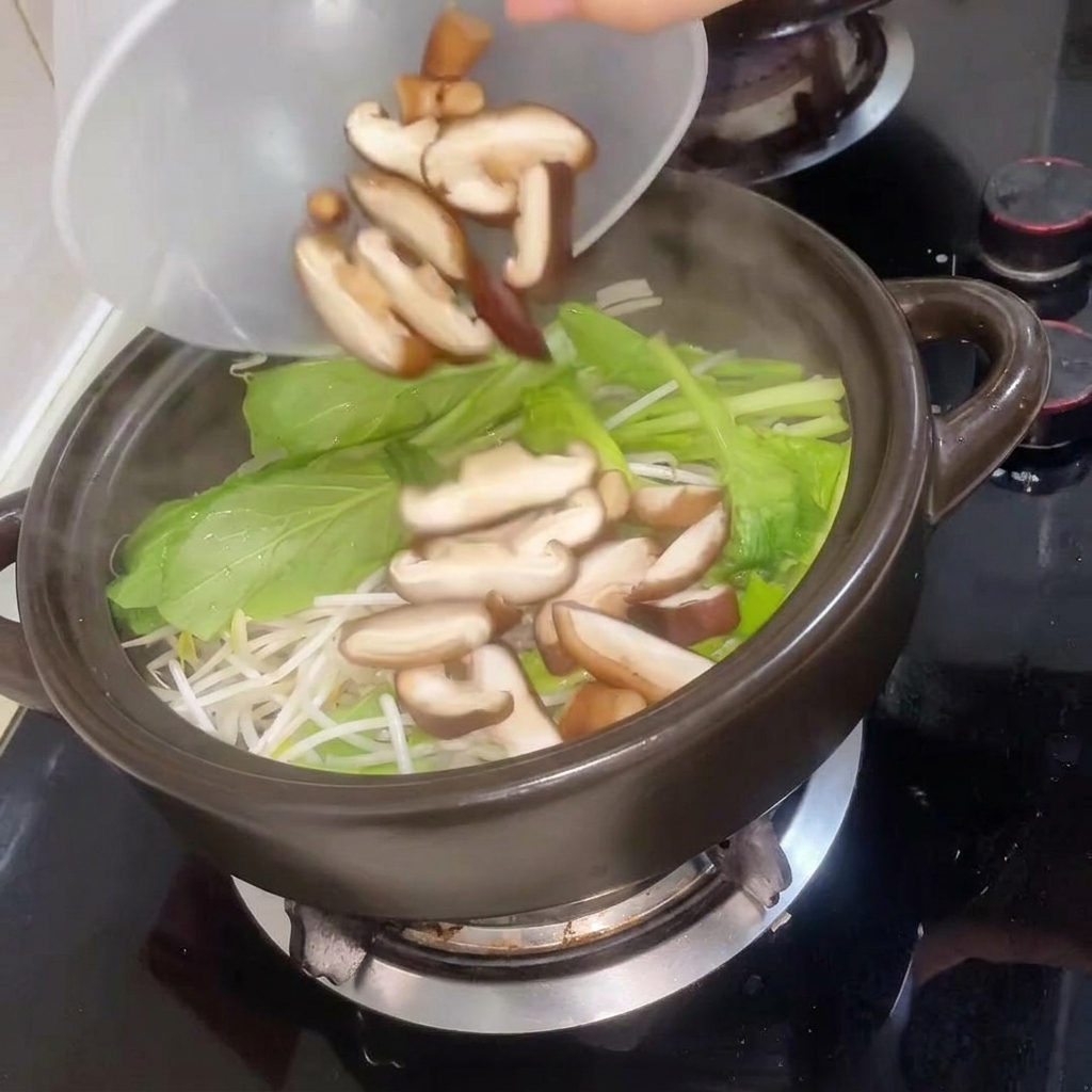 Setas shiitake rebanadas siendo añadidas a la olla seguidas de agua caliente.