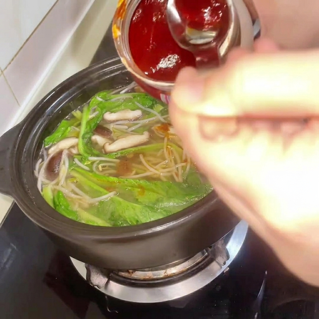 Pasta de chile coreana siendo añadida al estofado mientras se remueve.