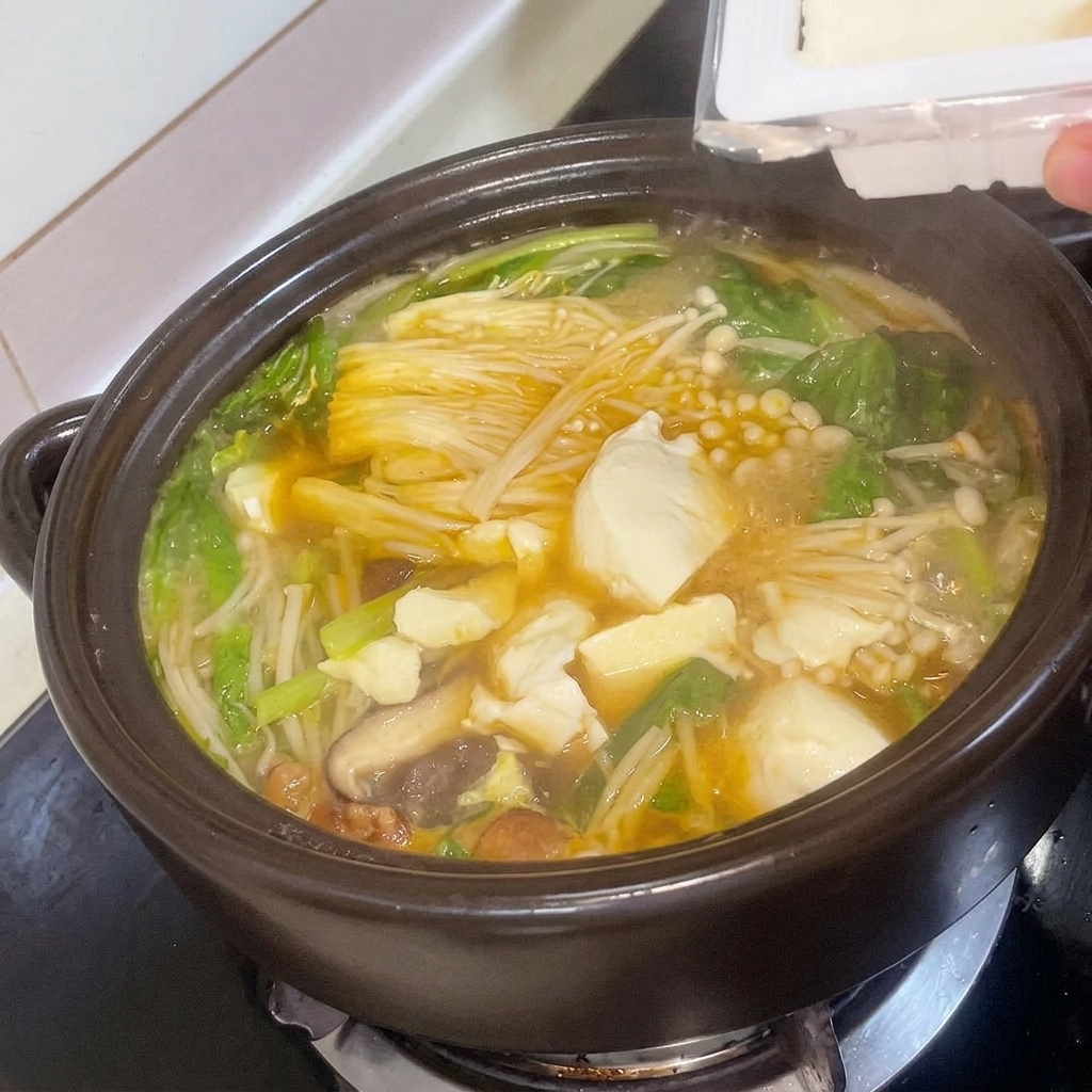 Cubos de tofu fresco siendo añadidos cuidadosamente al estofado.