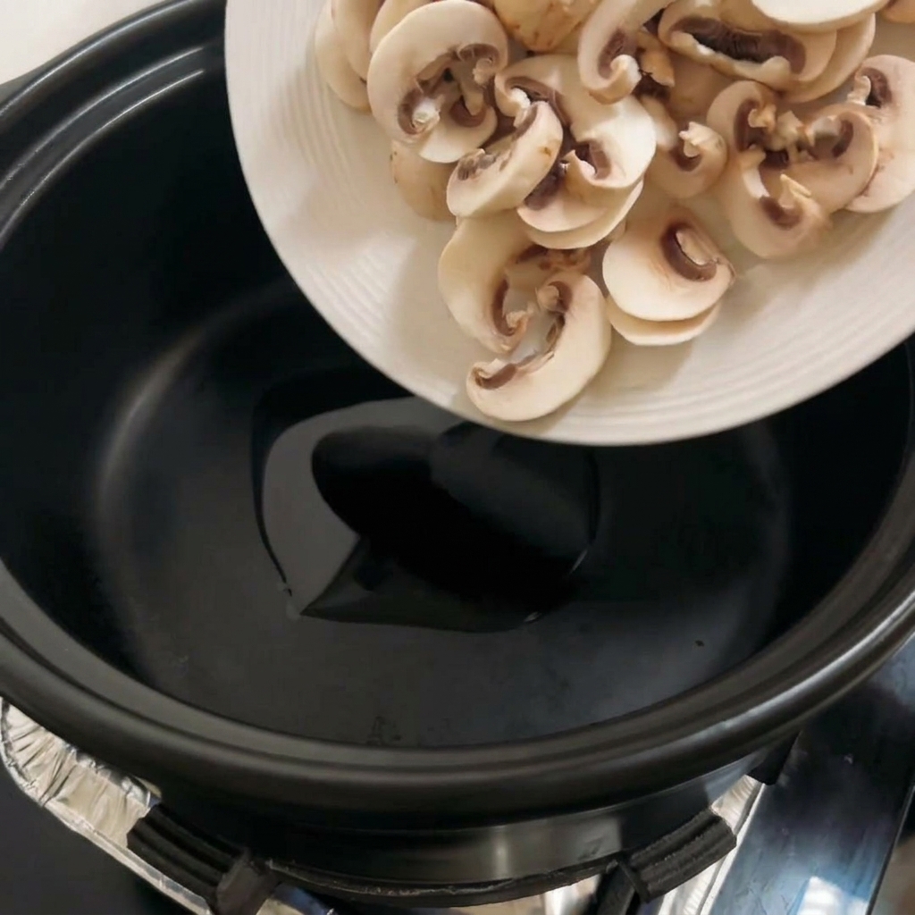 Champiñones portobello en rodajas cocinándose en una olla negra, dorándose.