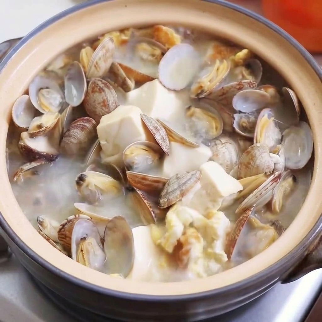 Primer plano de caldo de pollo en polvo, sal y pimienta espolvoreándose en la sopa burbujeante.