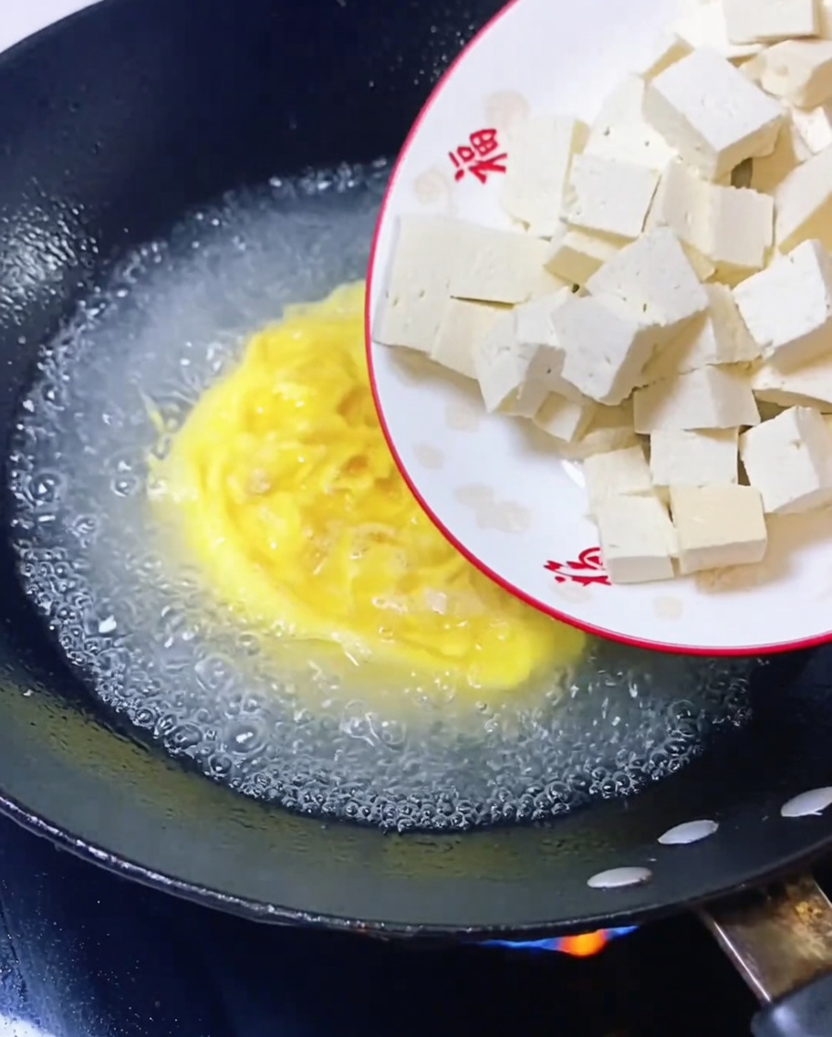 Cubos de tofu añadidos al caldo de huevo en ebullición.