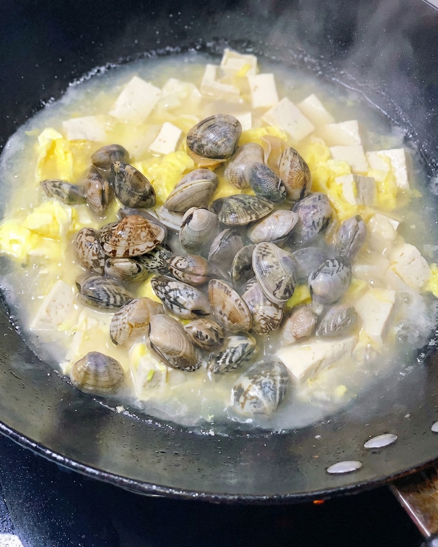 Almejas frescas añadidas a la olla con el tofu y los huevos.