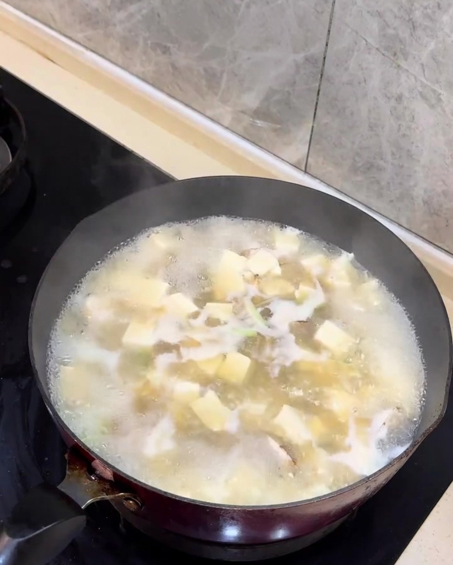 Trozos de cebollino verde fresco siendo añadidos a la sopa terminada.