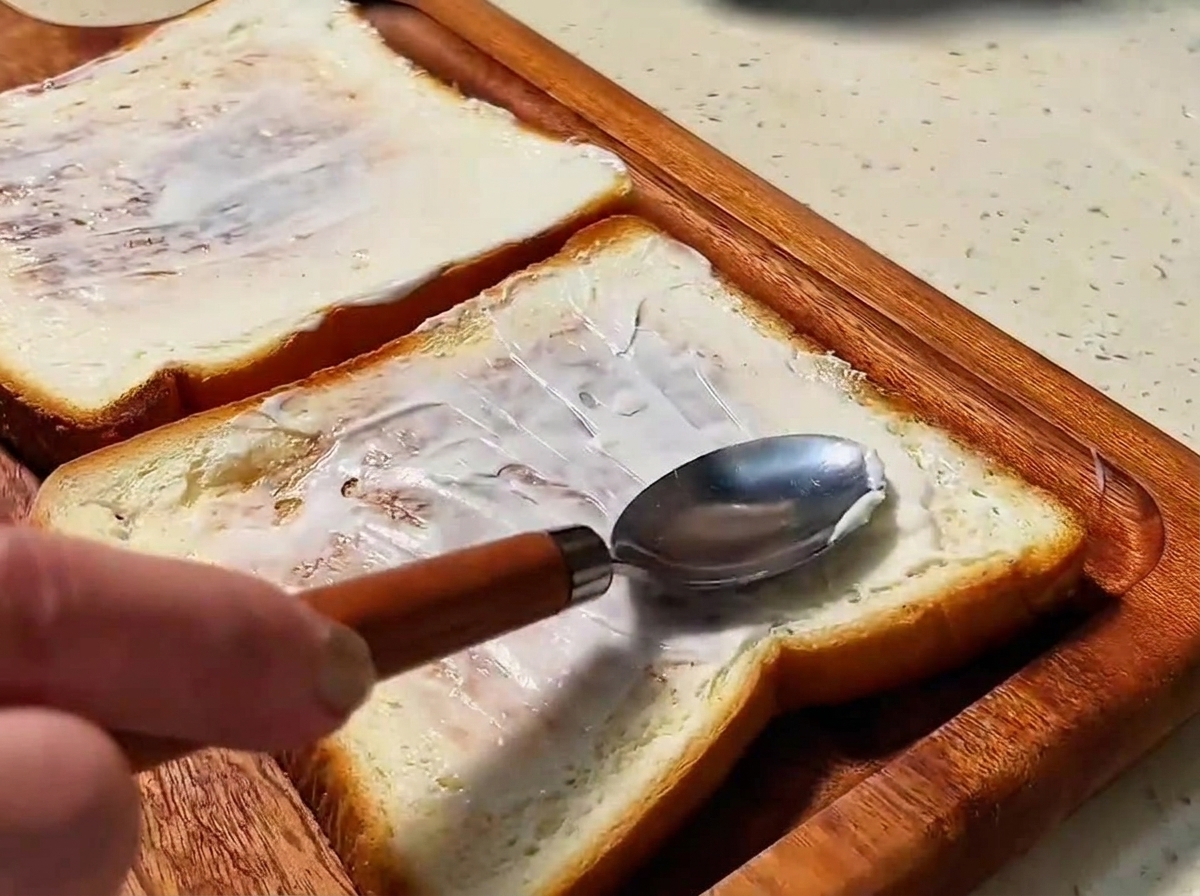 Dos rebanadas de pan tostado dorado untadas con una fina capa de mayonesa.