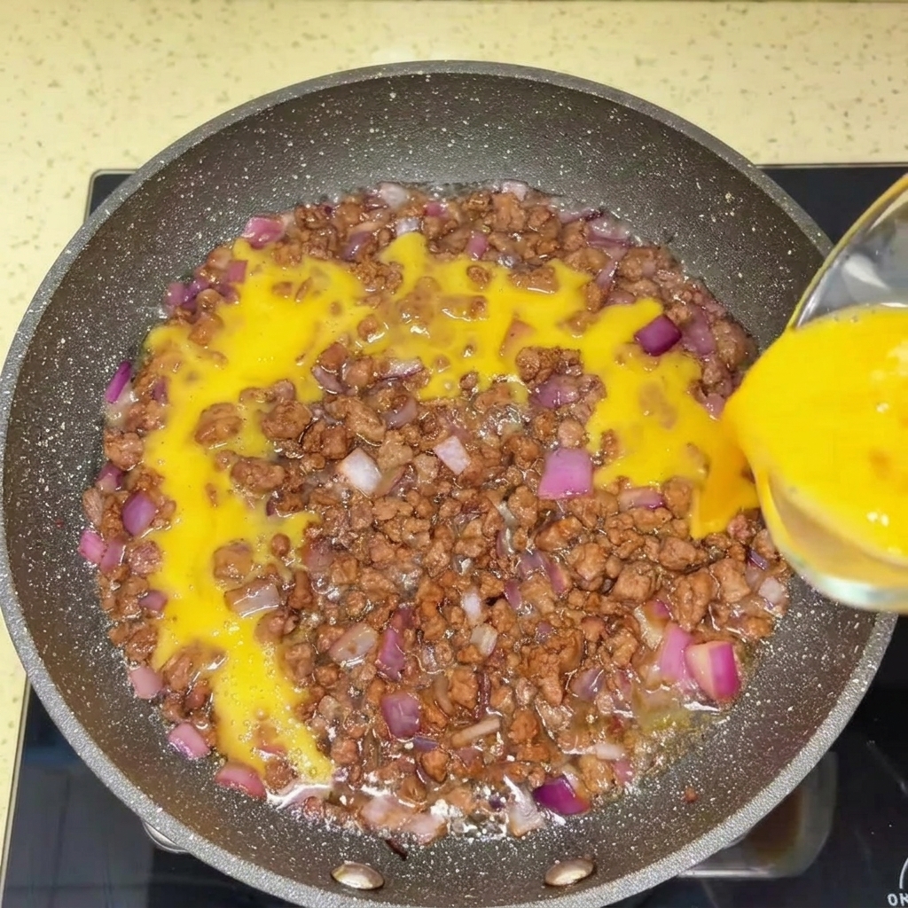 Ternera picada desmenuzándose en una sartén caliente con una espátula.