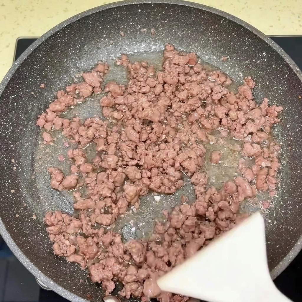 Una sartén conteniendo ternera y cebollas cocinadas.