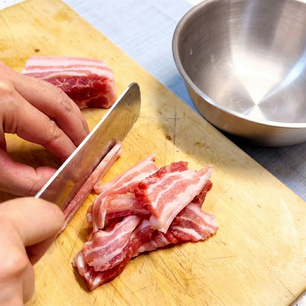 Tiras de panceta de cerdo cruda dispuestas en una tabla de cortar de madera.