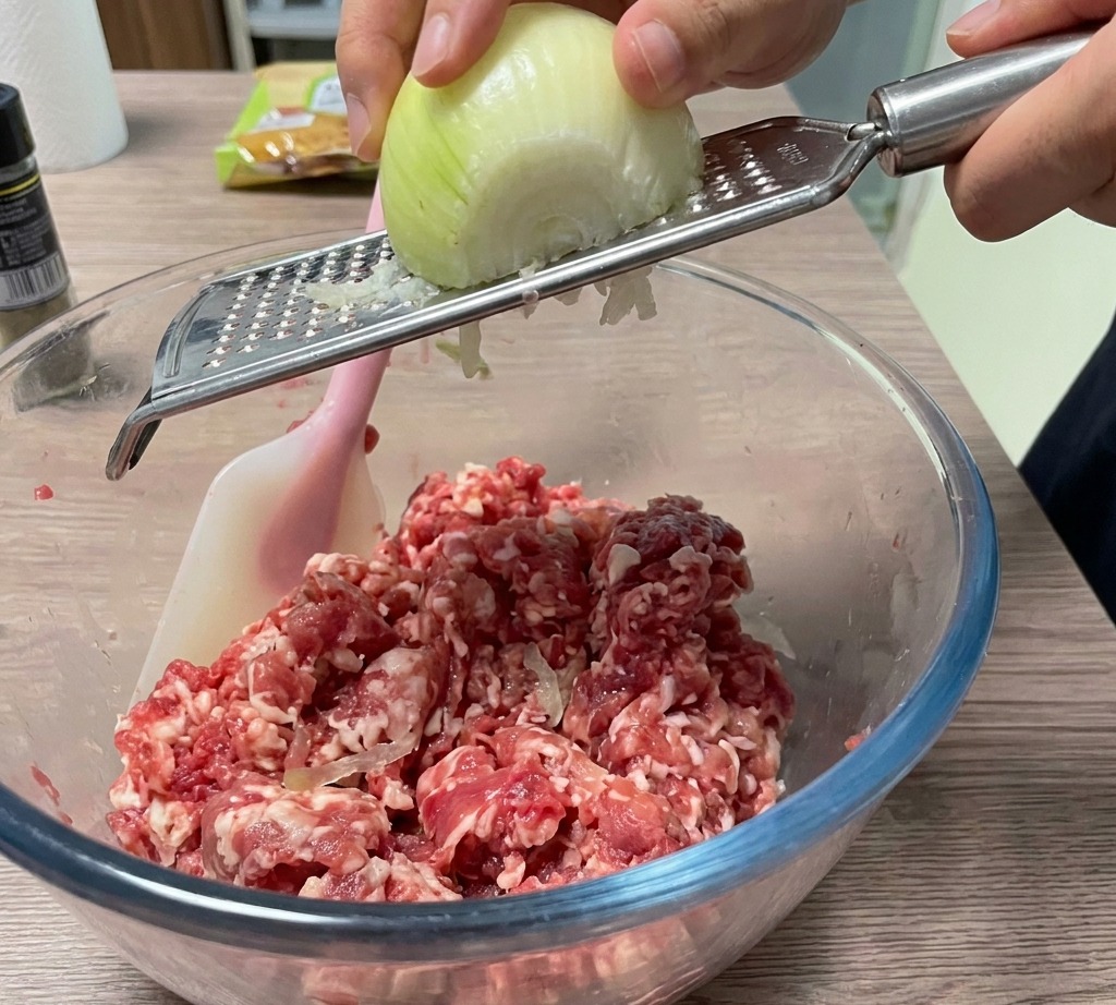 Cebolla siendo rallada fresca en el bol de carne.