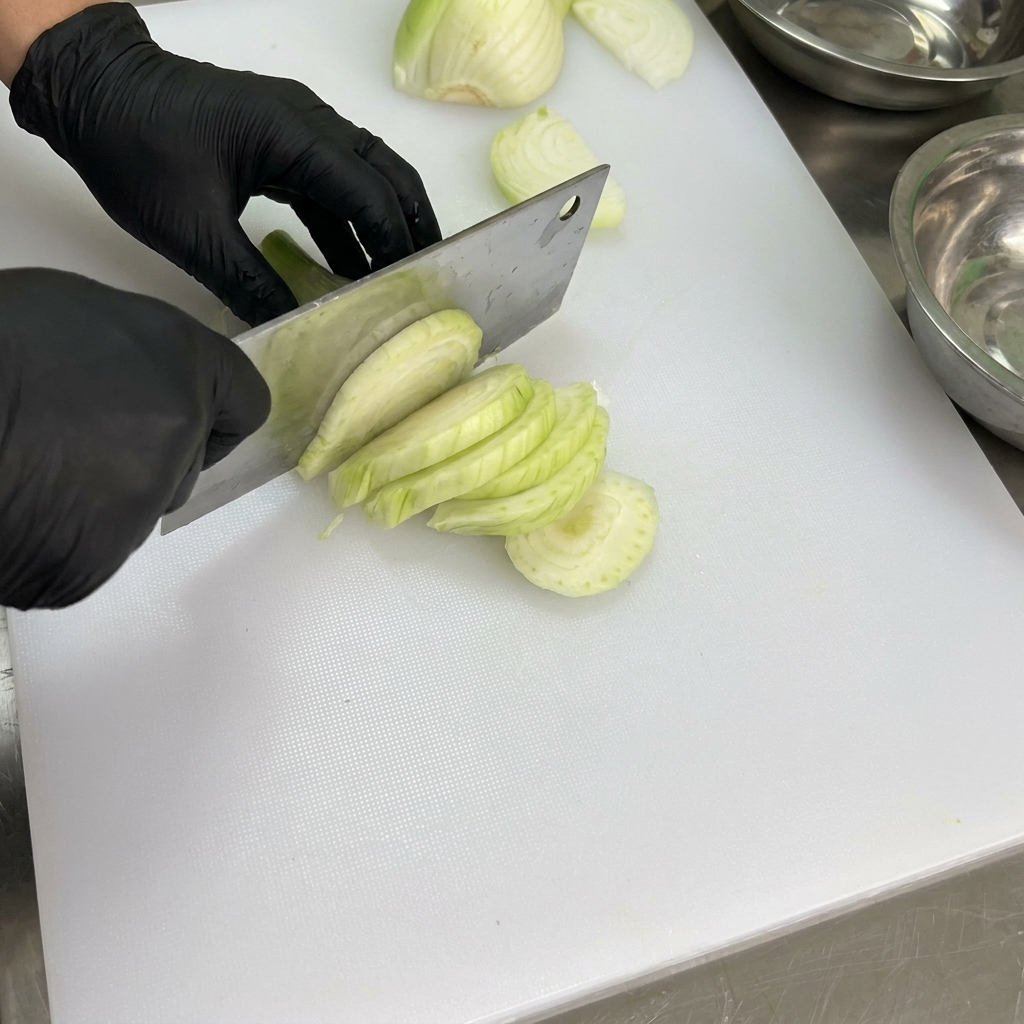Pimientos frescos siendo limpiados y sin semillas en una tabla de cortar blanca.