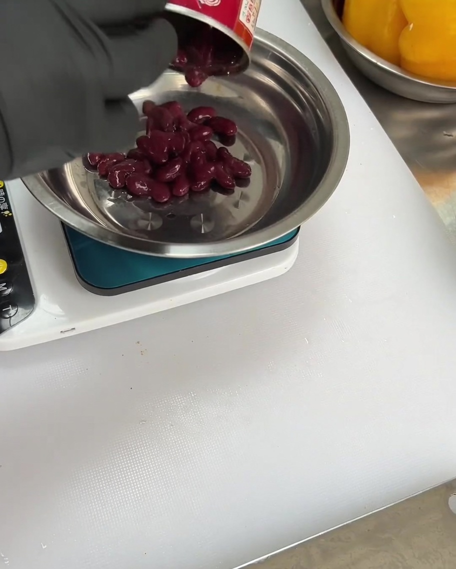 Frijoles rojos siendo añadidos al tazón con especias y pimientos.