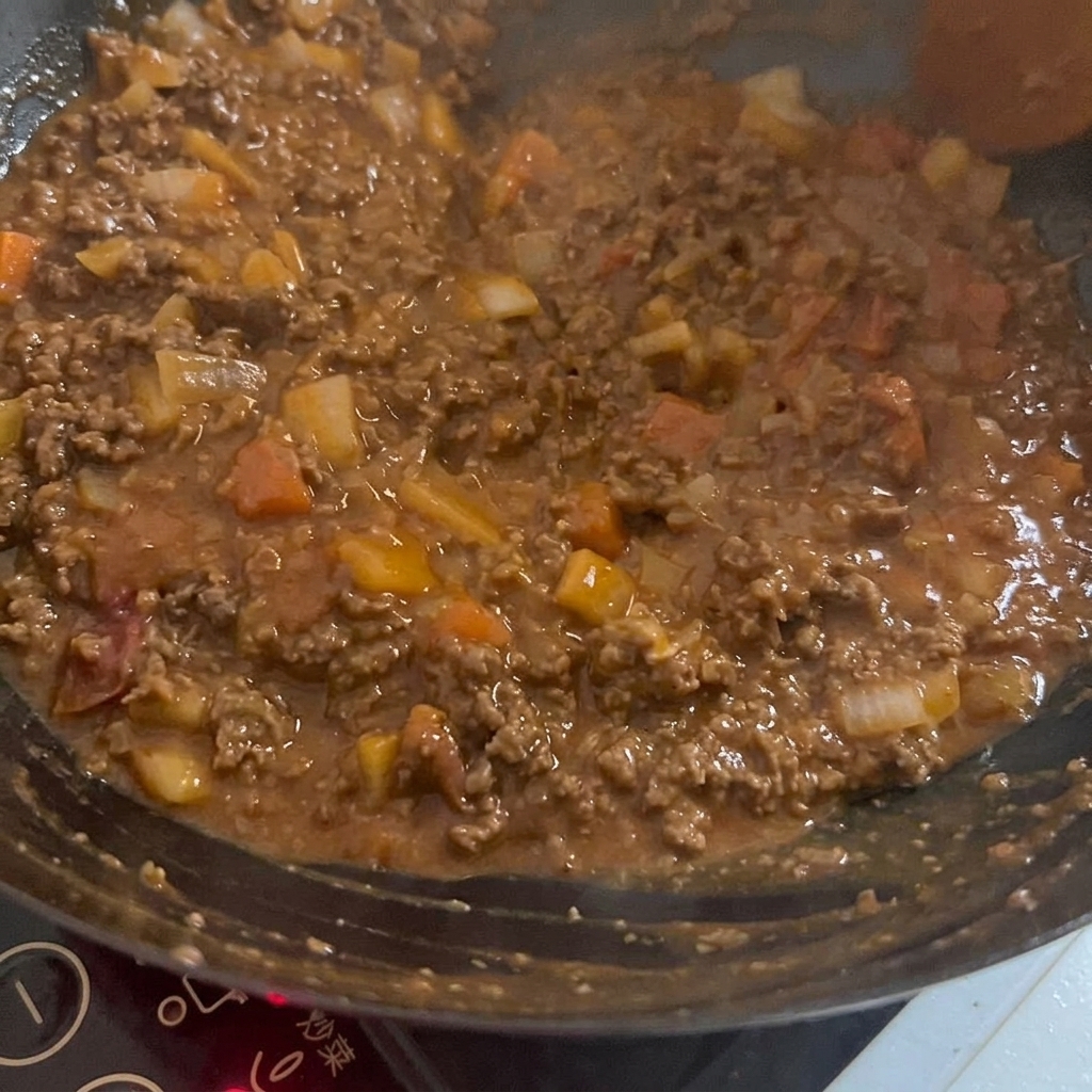 Una salsa rica y oscura siendo mezclada con la carne y vegetales en un wok caliente.