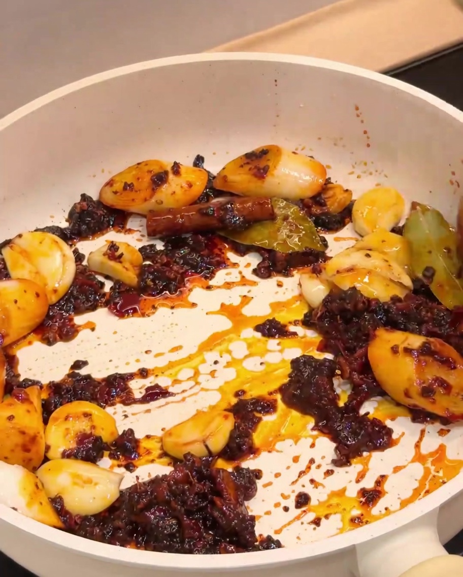 Cangrejos de río fritos mezclándose con la base de especias aromáticas en una sartén.
