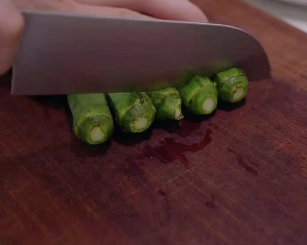 Okra verde fresca cortada en rodajas pequeñas sobre una tabla de cortar de madera.