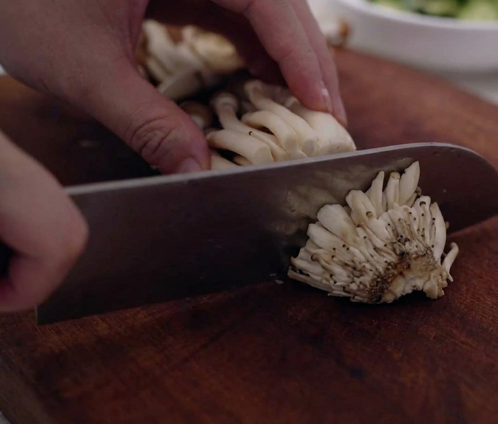 Racimos de champiñones shimeji recortados y separados en una tabla de cortar.