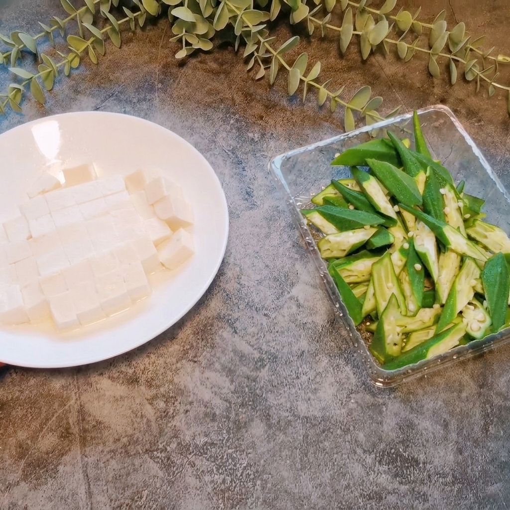 Un bloque de tofu suave siendo cortado en cubos pequeños y uniformes sobre un plato blanco.