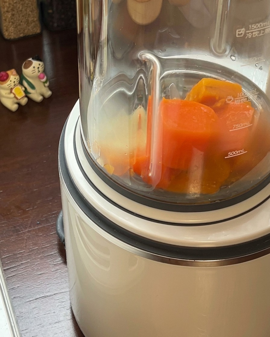 Mezcla de calabaza y zanahoria cocidas siendo vertidas en el vaso de una licuadora de alta potencia.