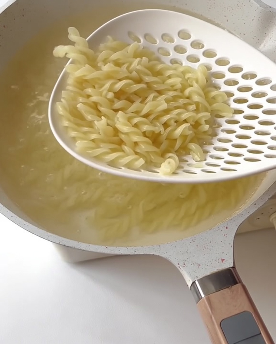 Trozos de espárragos verdes cocinándose en agua hirviendo.
