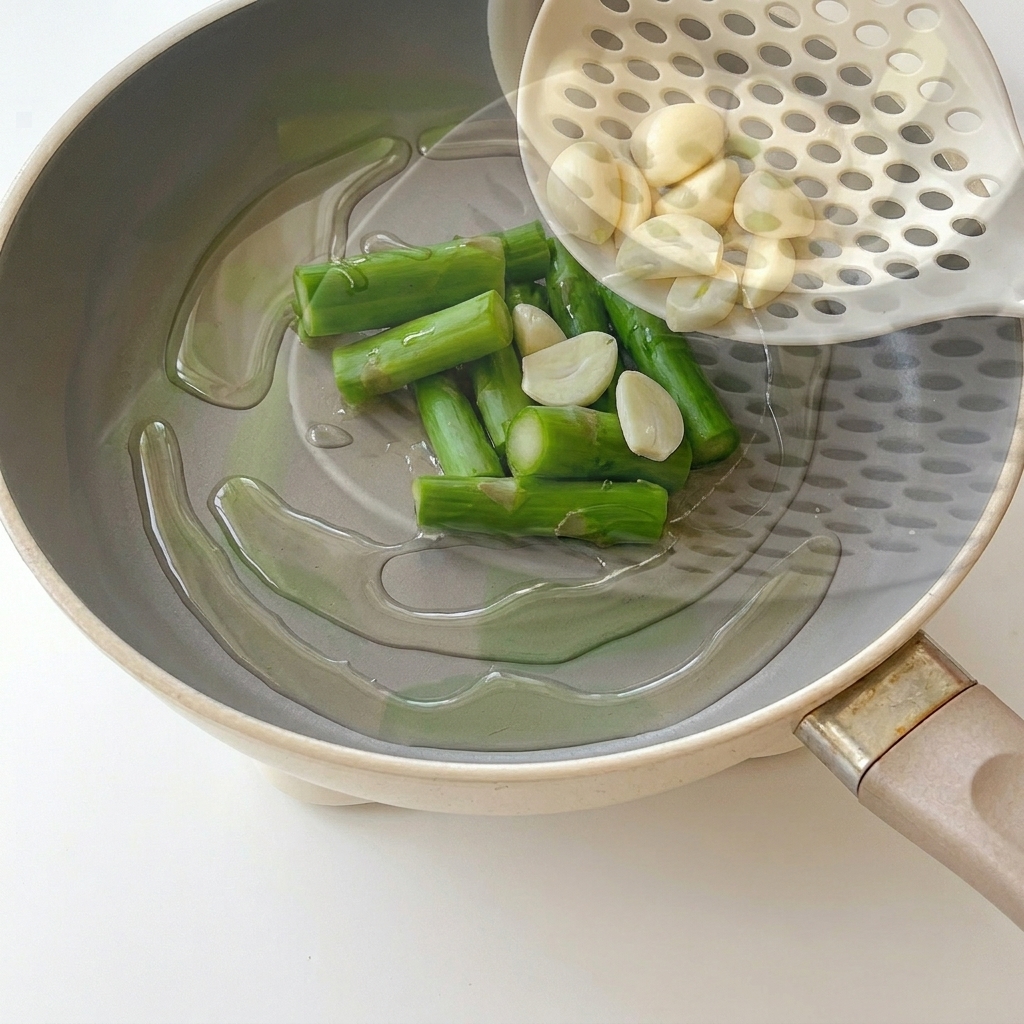 Mitades de ajo salteándose en una sartén con aceite caliente.