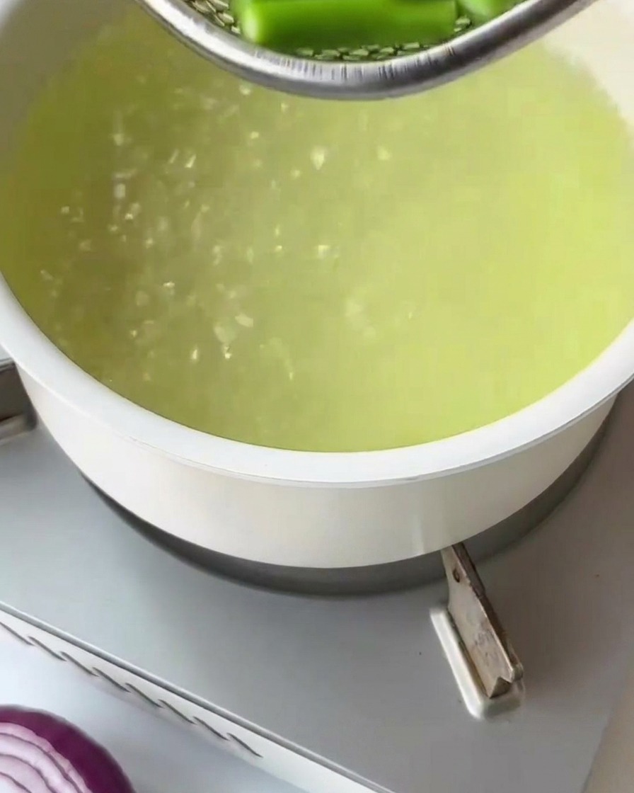 Pasta fusilli seca siendo agregada a una olla con agua hirviendo.