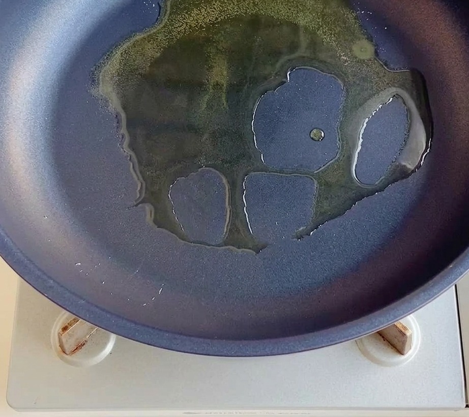 Cebollas rojas picadas cocinándose en una sartén con aceite caliente.