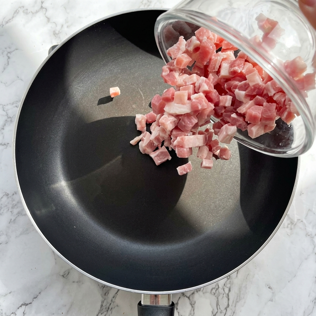 Bacon troceado friéndose en una sartén hasta que esté dorado y crujiente.