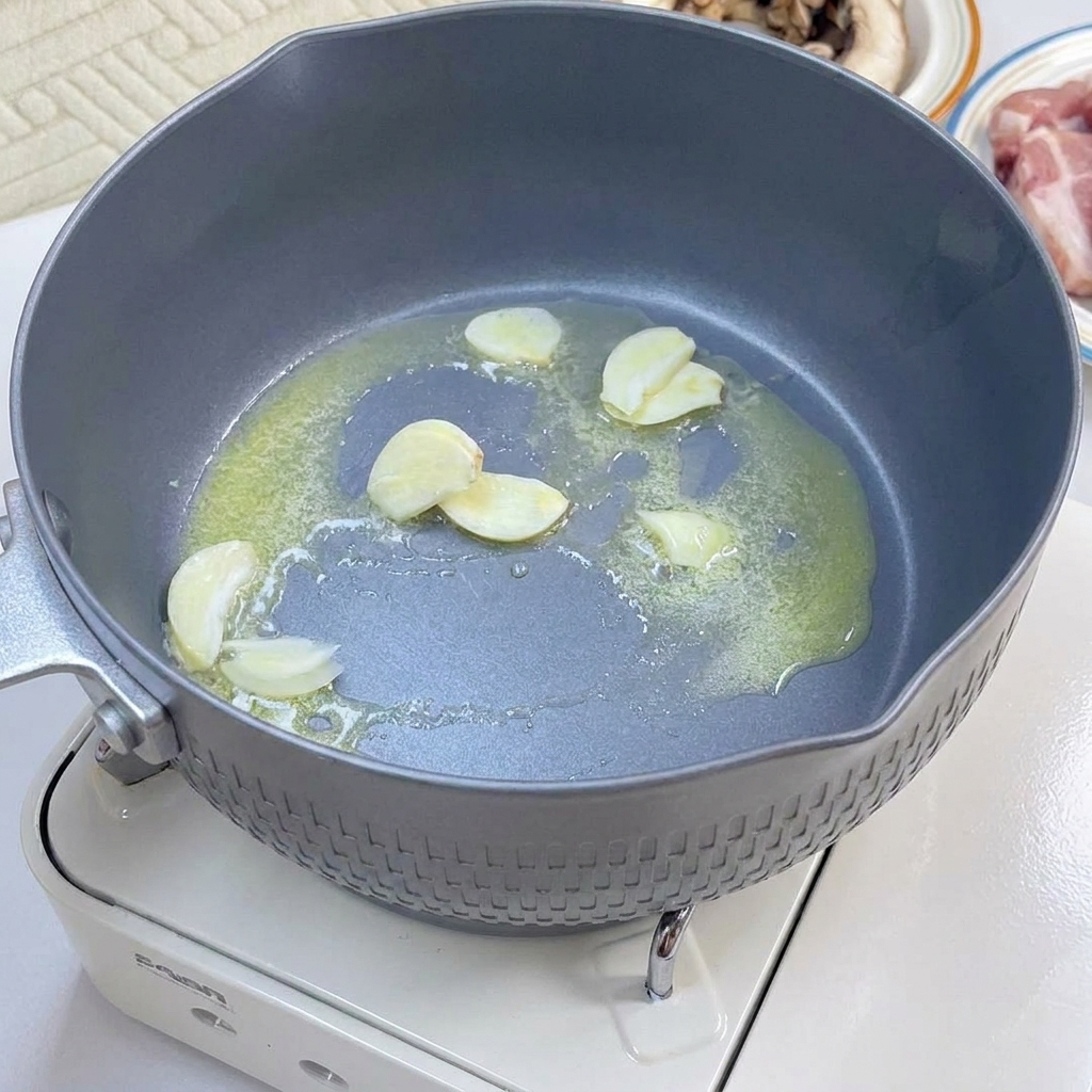 Tiras de tocino y láminas de champiñones sofriéndose en una sartén hasta dorar.