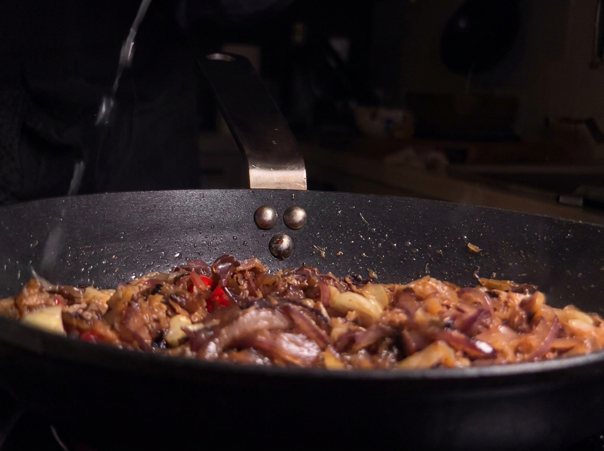 Zumo de limón fresco siendo exprimido sobre la sartén con las anchoas y los aromáticos.