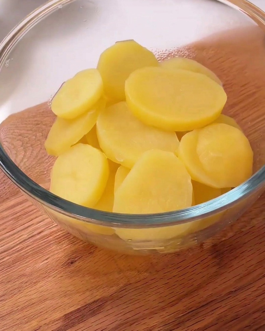 Láminas de patata al vapor en un bol con pimienta negra y almidón blanco encima.