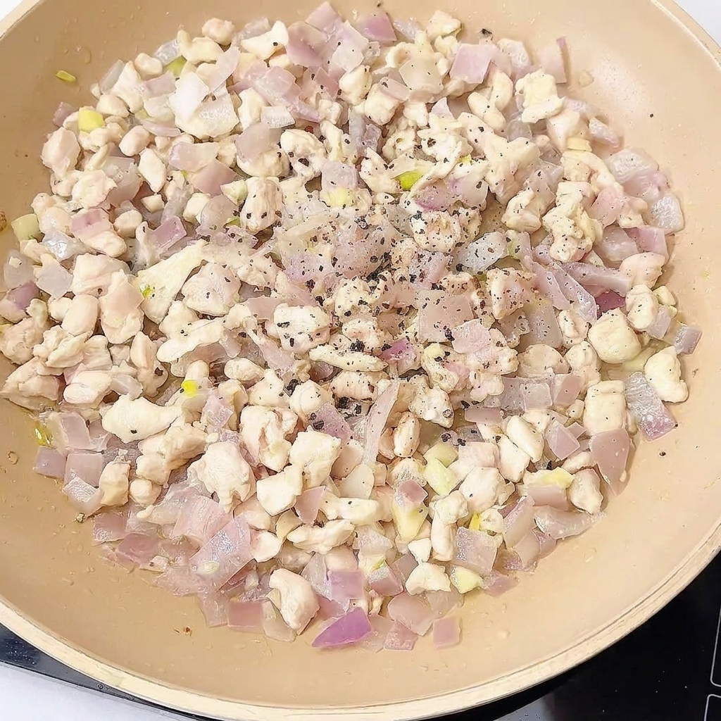Salteado de pollo en la sartén siendo sazonado con especias y salsas.