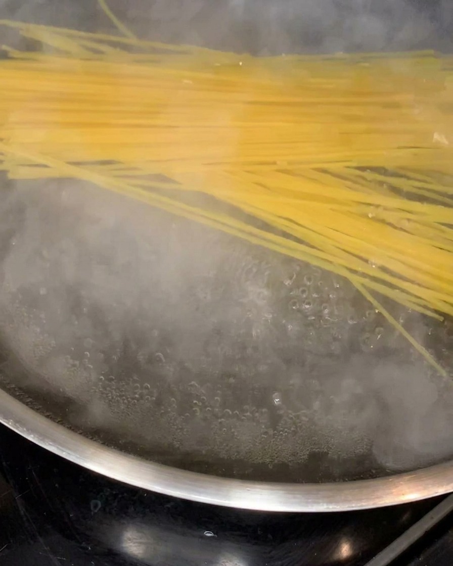 Fideos de espagueti ablandándose y cocinándose en una olla grande con agua hirviendo.