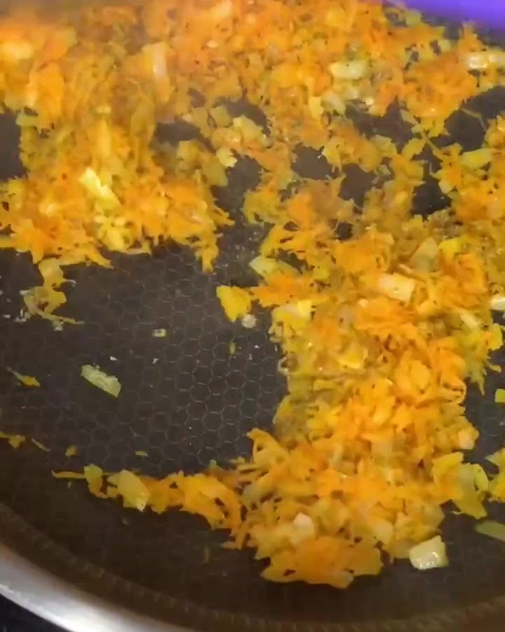 Carne picada de res siendo mezclada con zanahorias y cebollas sofritas en una sartén antiadherente.