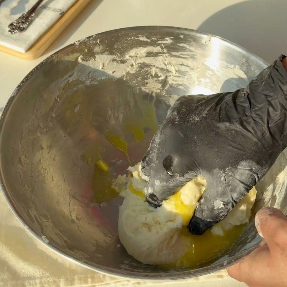 Mantequilla derretida siendo vertida sobre la masa en un tazón de metal.