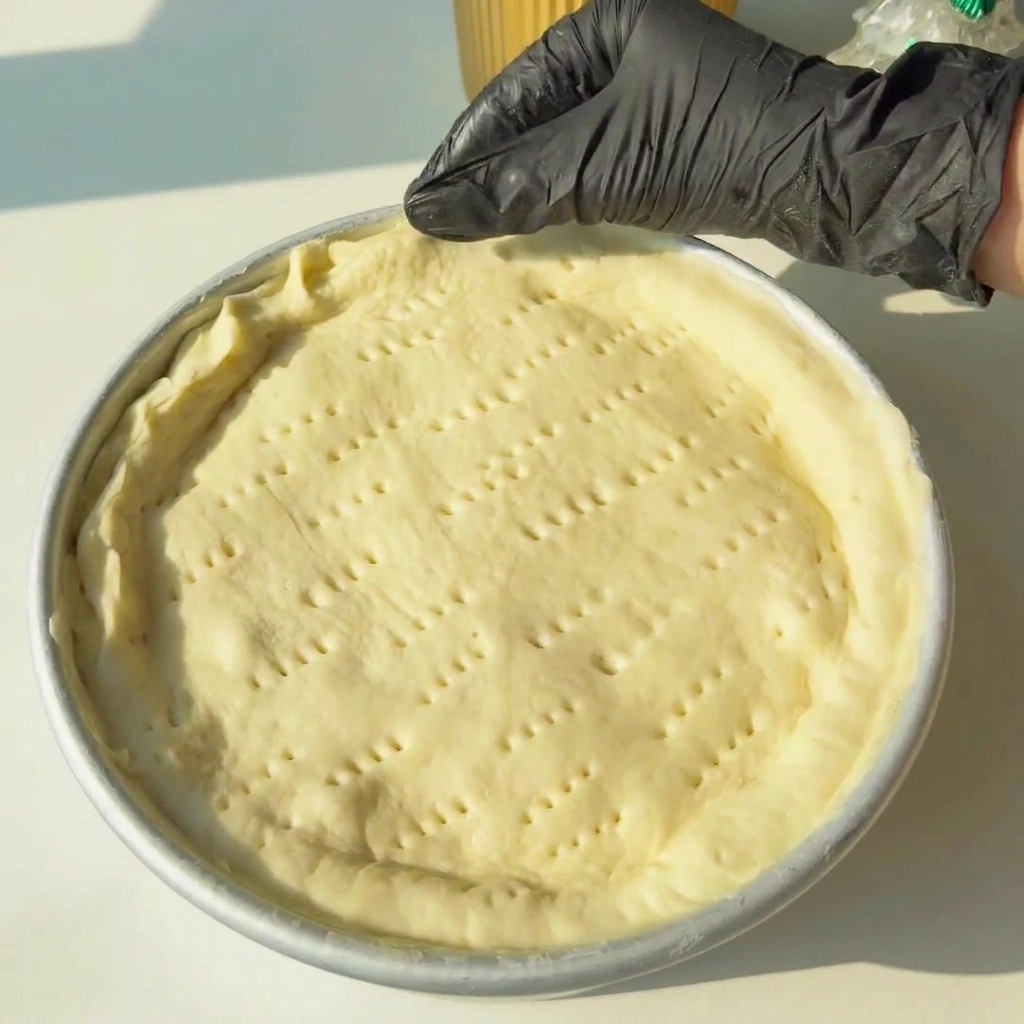 Manos pellizcando los bordes de la masa para sellar las capas superior e inferior.