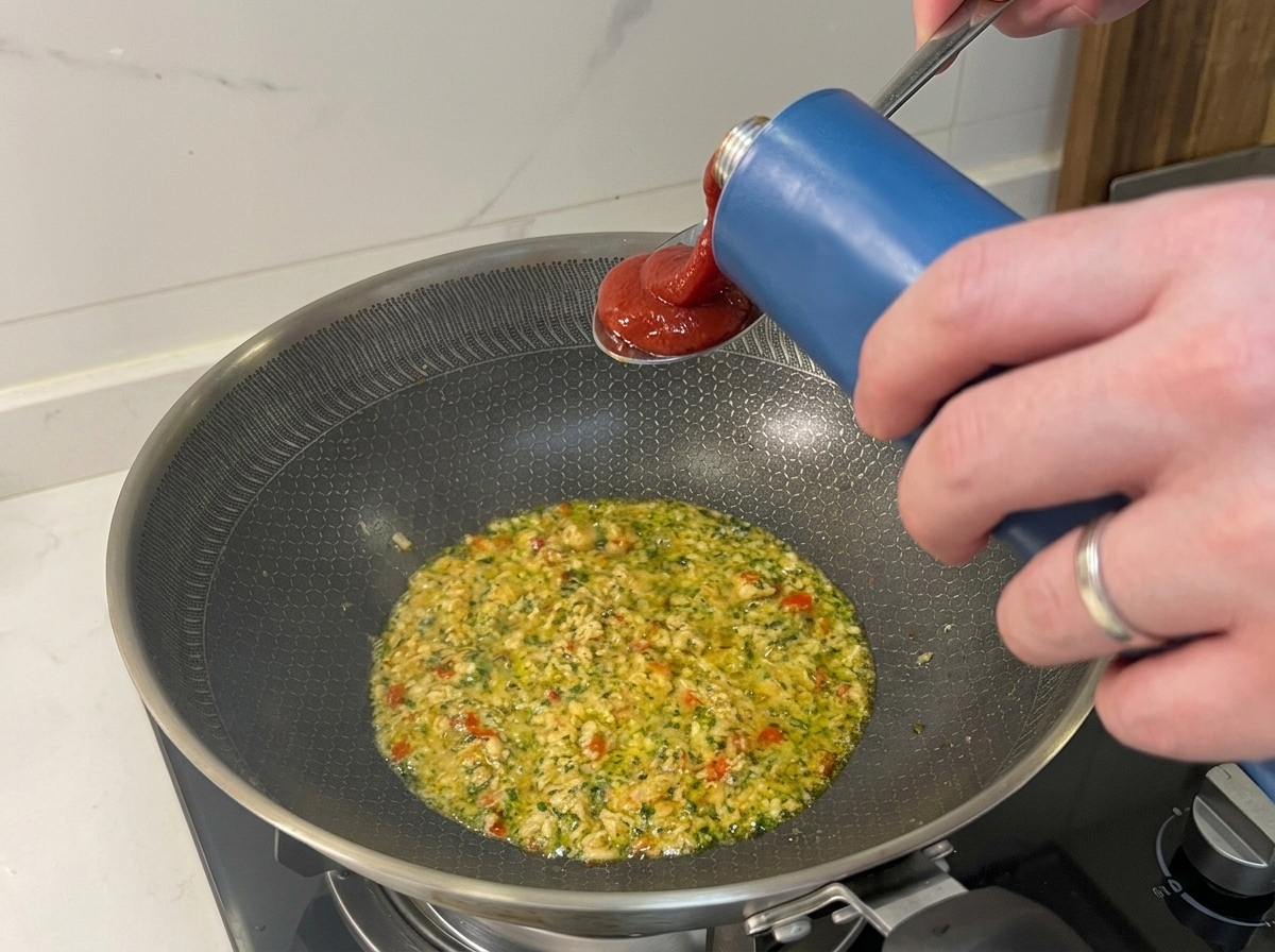 Tomate passata siendo vertido en la sartén con atún y sofrito.