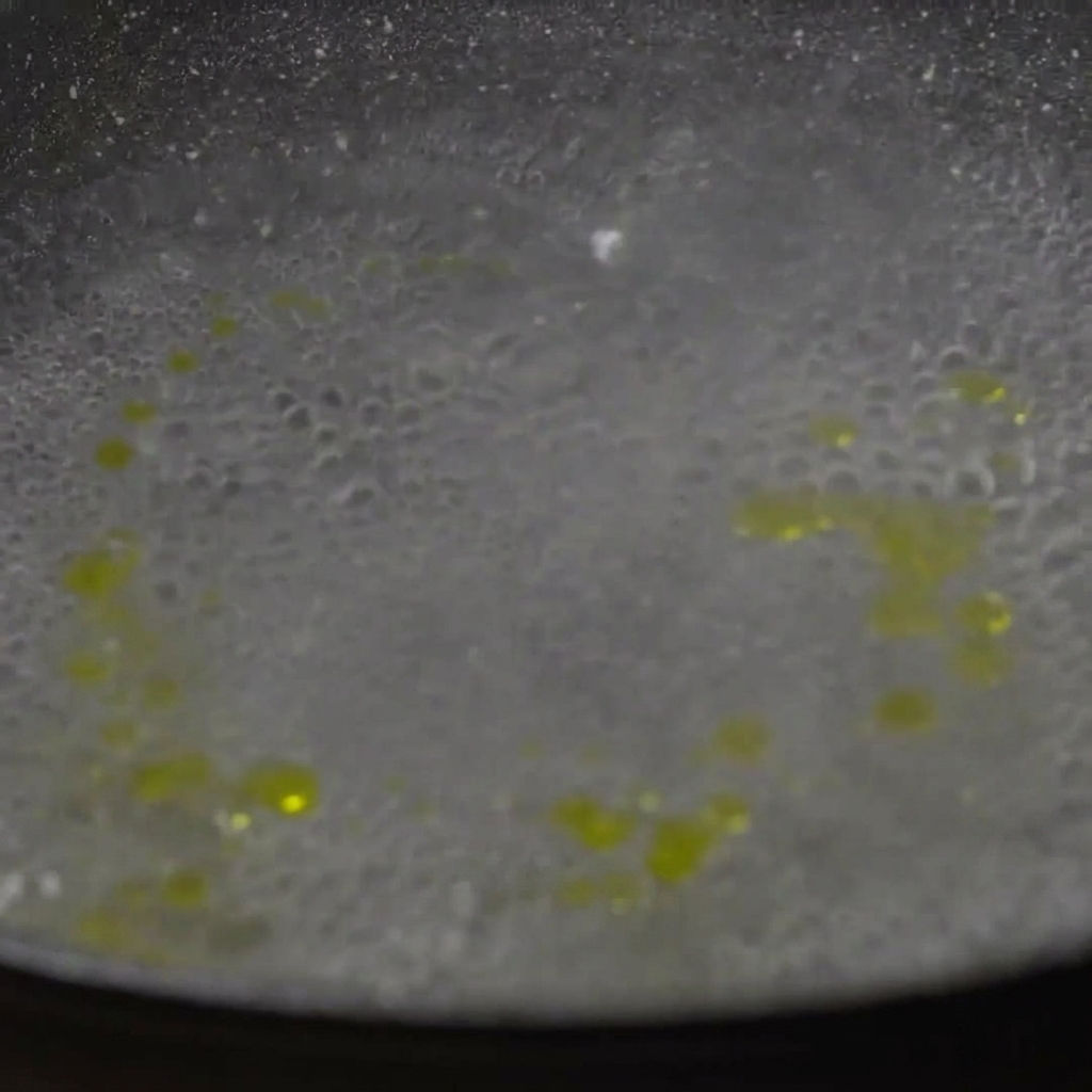 Pasta paccheri seca siendo añadida a una olla de agua hirviendo.