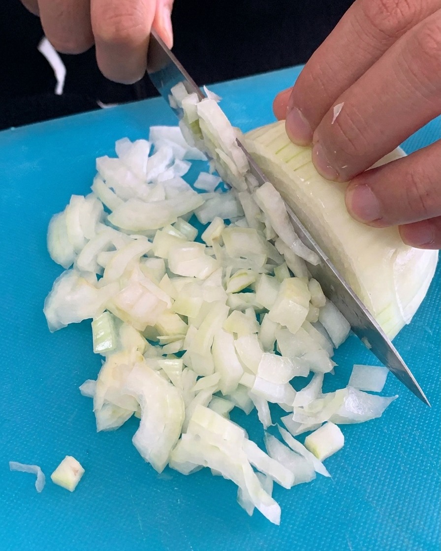 Pasta penne seca siendo añadida a una olla con agua hirviendo.