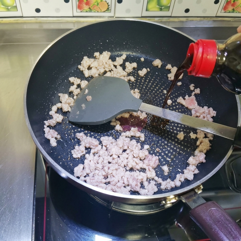 Salsa de soja líquida oscura siendo vertida desde una botella sobre carne picada dorada en una sartén caliente.