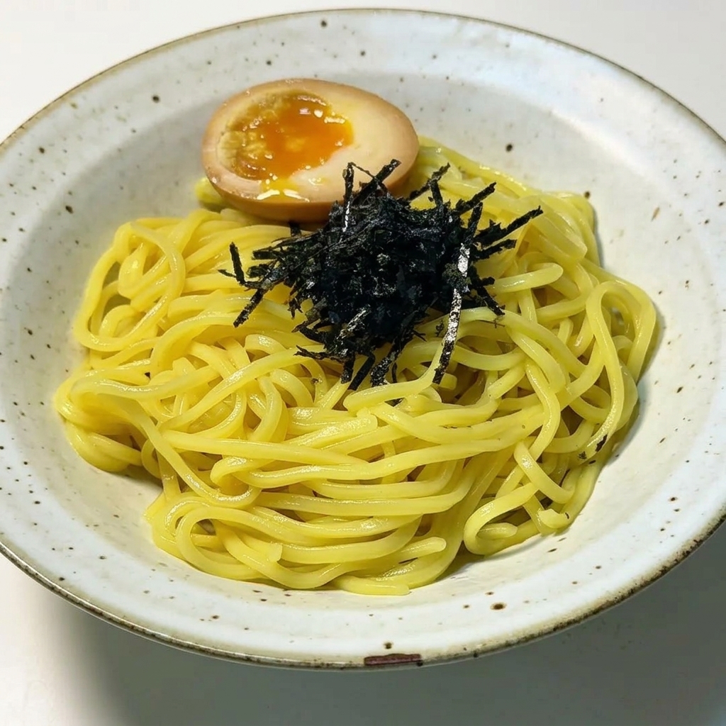 Fideos ramen decorados con tiras de alga nori y un huevo pasado por agua cortado por la mitad.