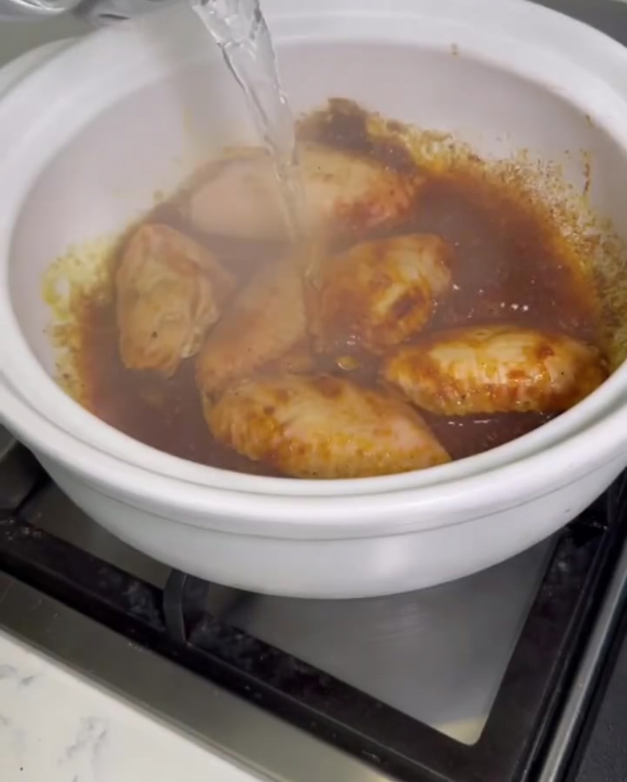 Agua clara cayendo sobre las alitas de pollo en la olla burbujeante.
