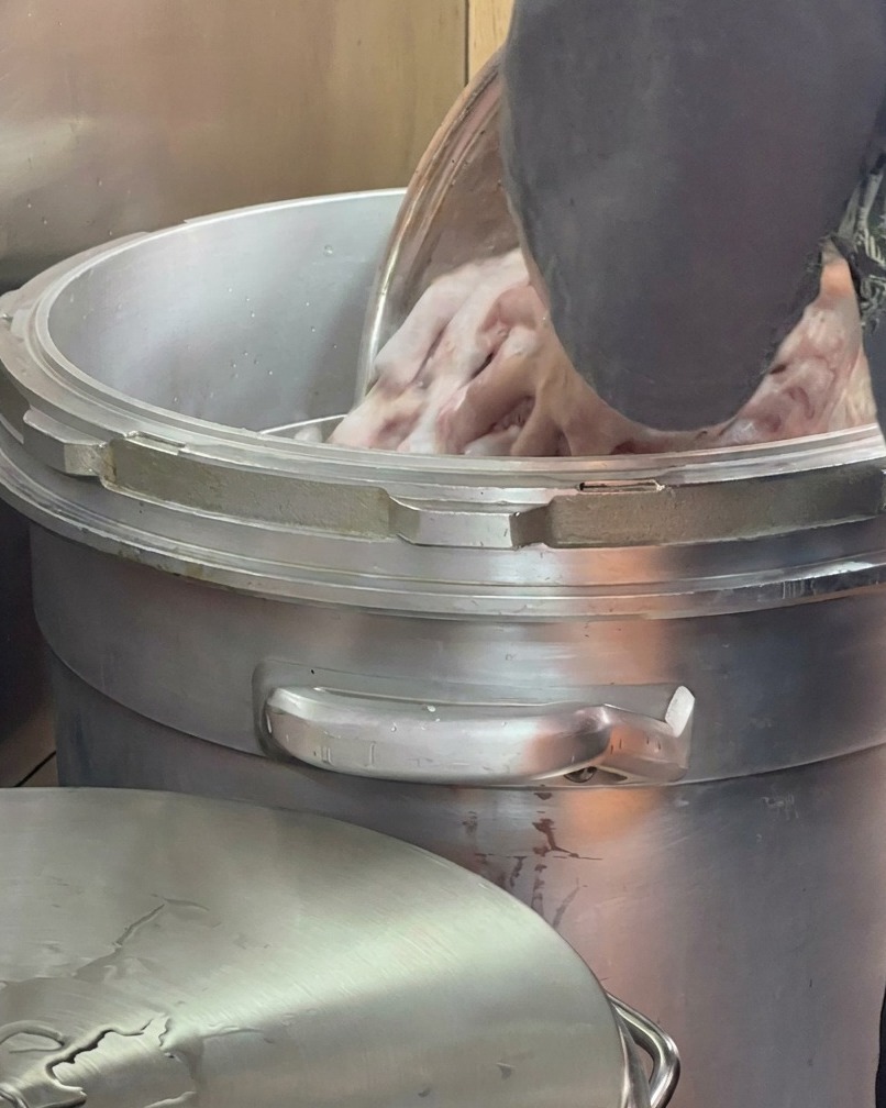 Agua fresca siendo vertida sobre los huesos dentro de una olla grande.