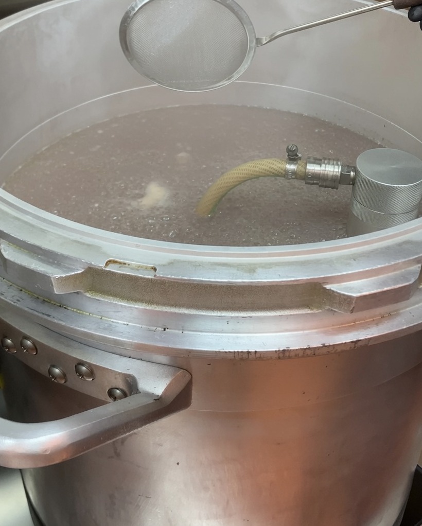 Eliminando la espuma de la superficie del caldo hirviendo con una espumadera de malla.