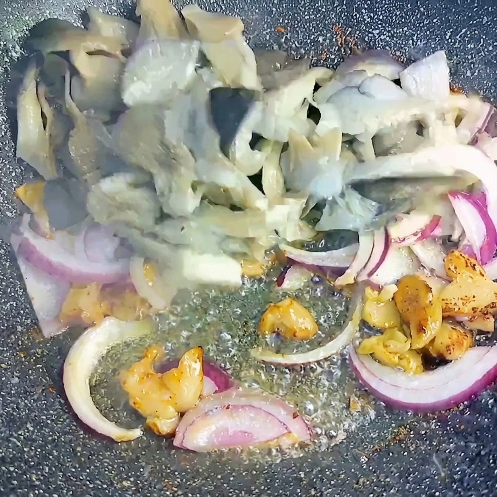 Setas ostra blanqueadas y cebollas rojas en rodajas mezcladas con trozos de panceta dorada en el wok.