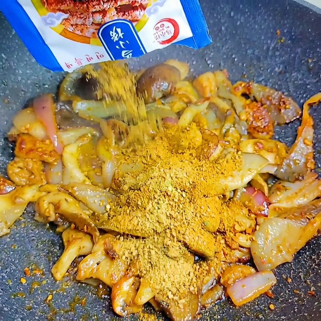 Un paquete azul vertiendo sazonador para barbacoa coreana sobre las setas y cebollas en el wok caliente.