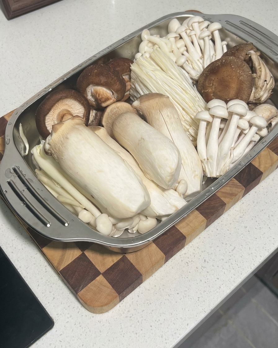 Pasta de camarones cruda siendo exprimida desde una manga pastelera hacia el centro de los sombreros de las setas shiitake.