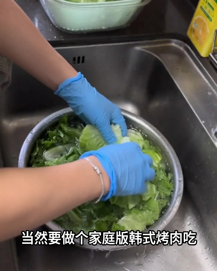 Hojas de lechuga verde fresca lavándose en un cuenco metálico grande lleno de agua.