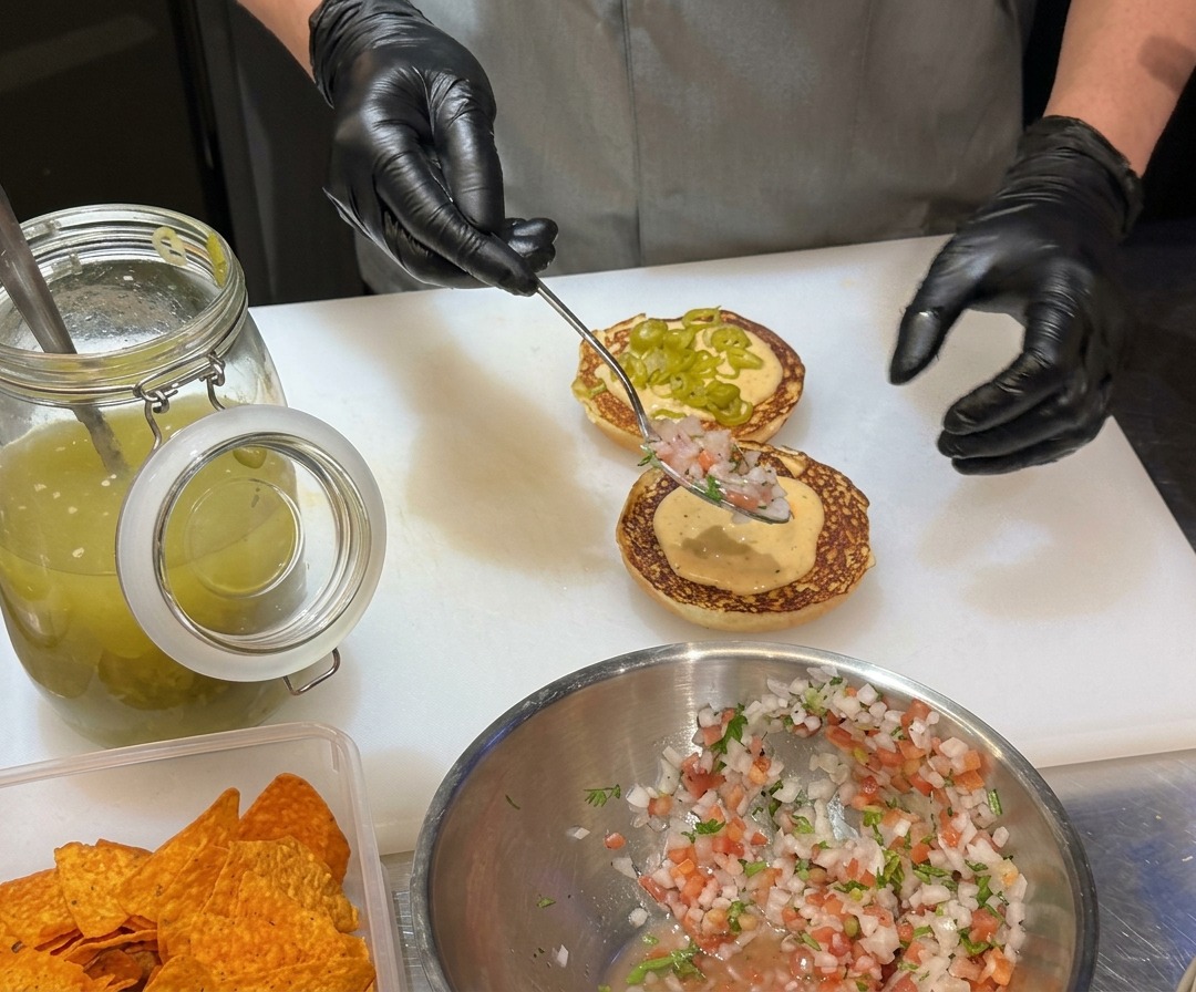 Mitades de pan de hamburguesa con mantequilla tostándose hasta dorarse en una plancha plana.