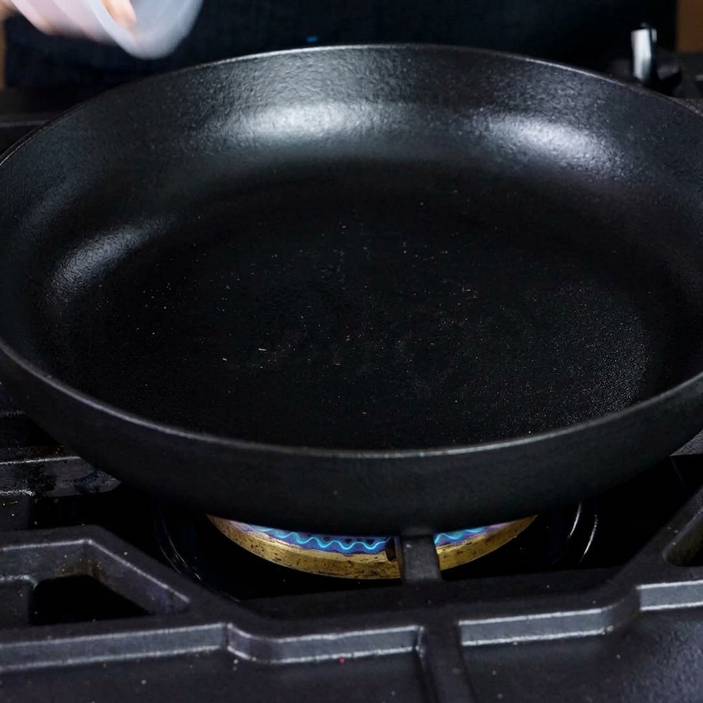 Trozos de tocino picado friéndose en una sartén caliente de hierro fundido.