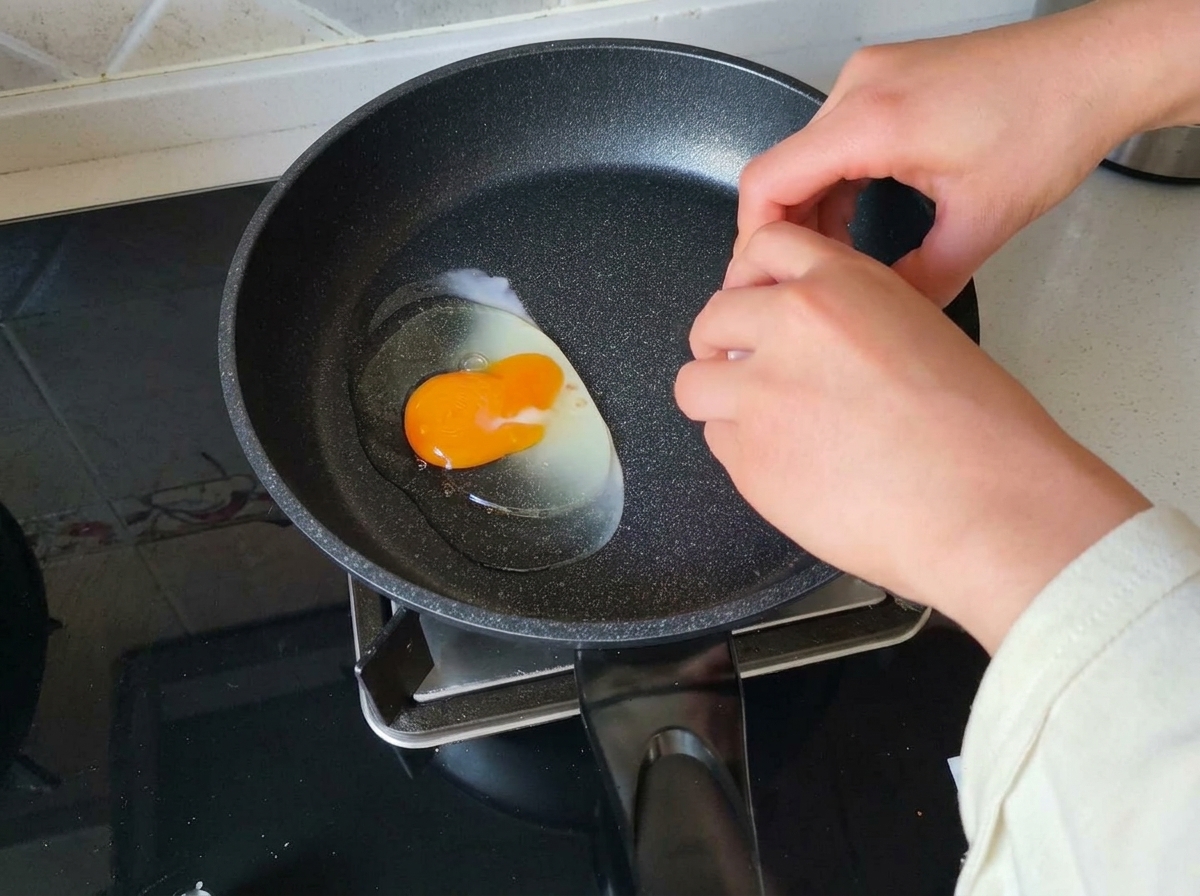 Rompiendo un huevo fresco en una sartén caliente.