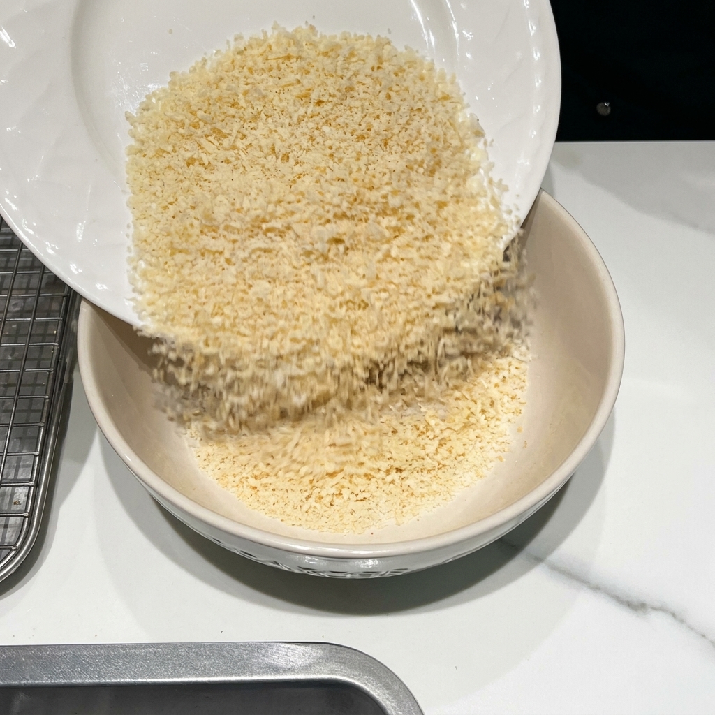 Un cuenco que contiene pan rallado, queso parmesano rallado y varias especias siendo mezclados.